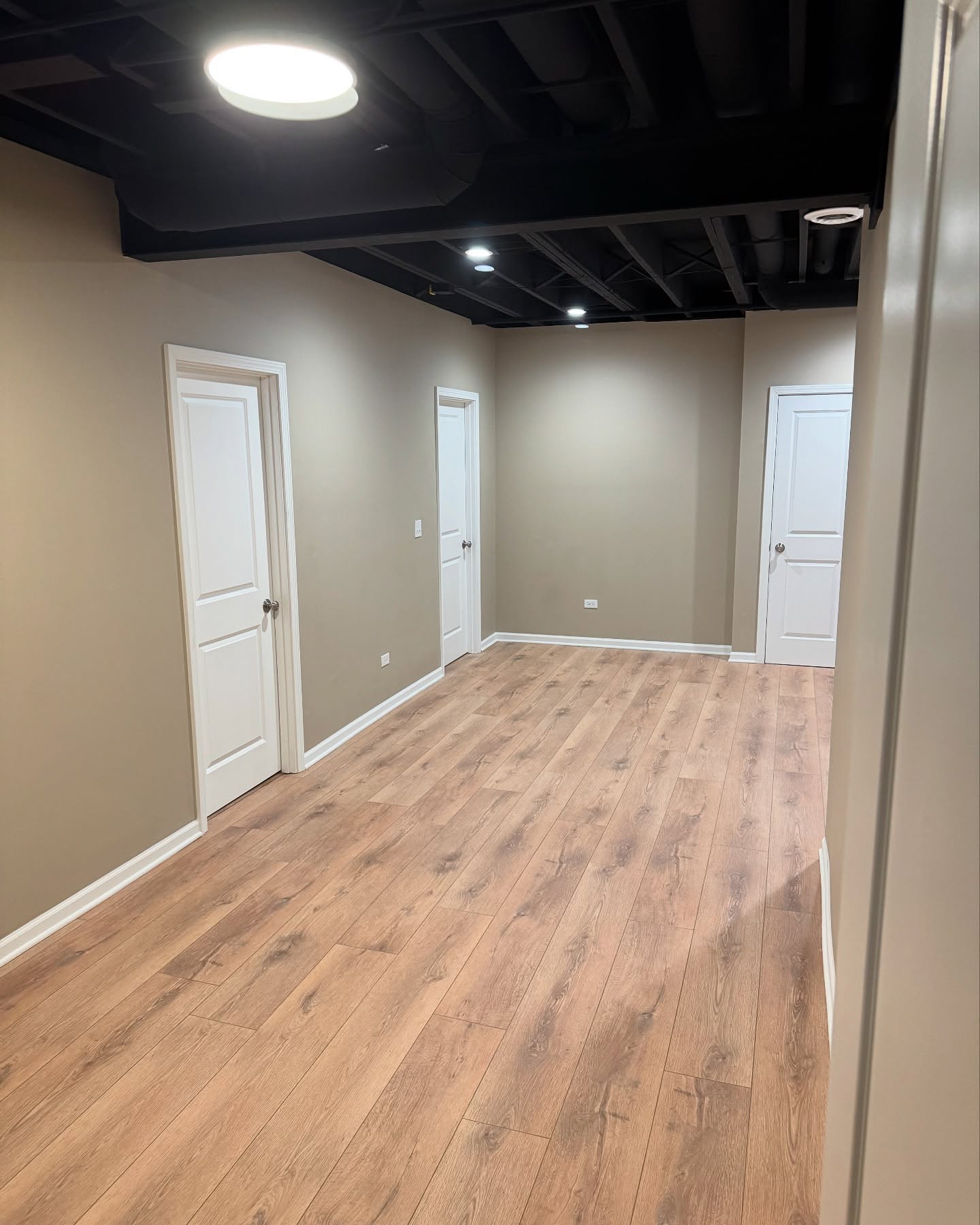 Finished basement with exposed black ceiling by ADR Construction