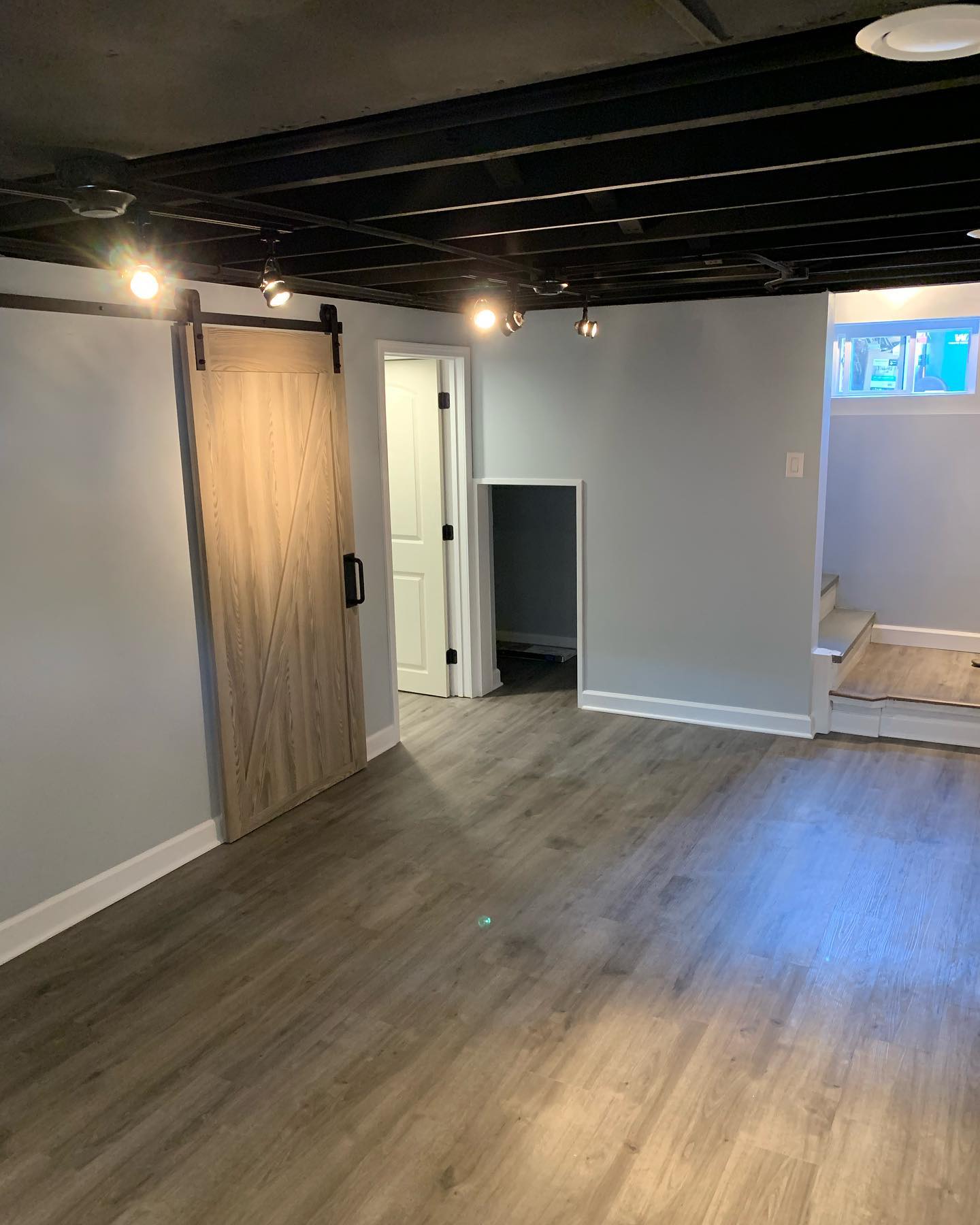 Finished basement space with custom barn door by ADR Construction