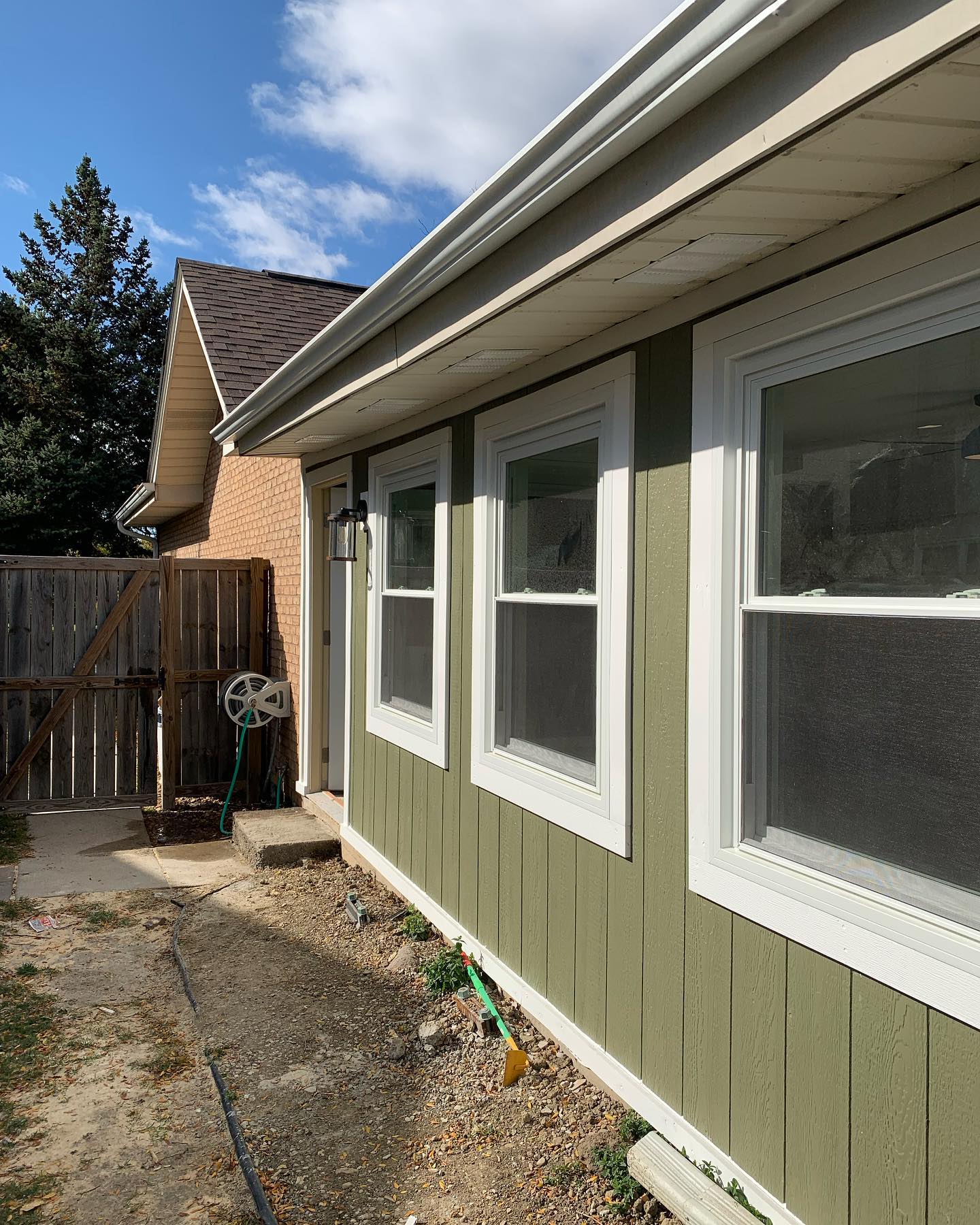 Exterior home facelift with green siding, white trim, and new windows by ADR Construction
